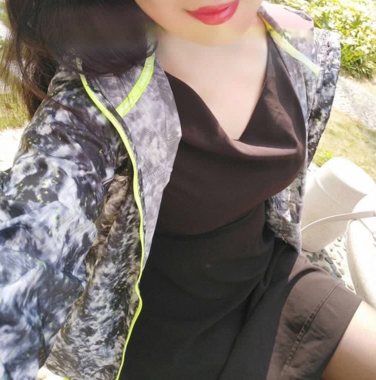 Close-up of glossy black pantyhose-clad legs stretched across sunlit pavement with subtle sheen